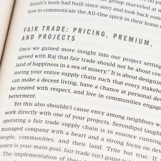 A close up of a book page, focusing on a chapter titled Fair Trade Pricing, Premium, and Projects. The text discusses fair trade concepts, emphasizing equitable supply chain practices for community betterment