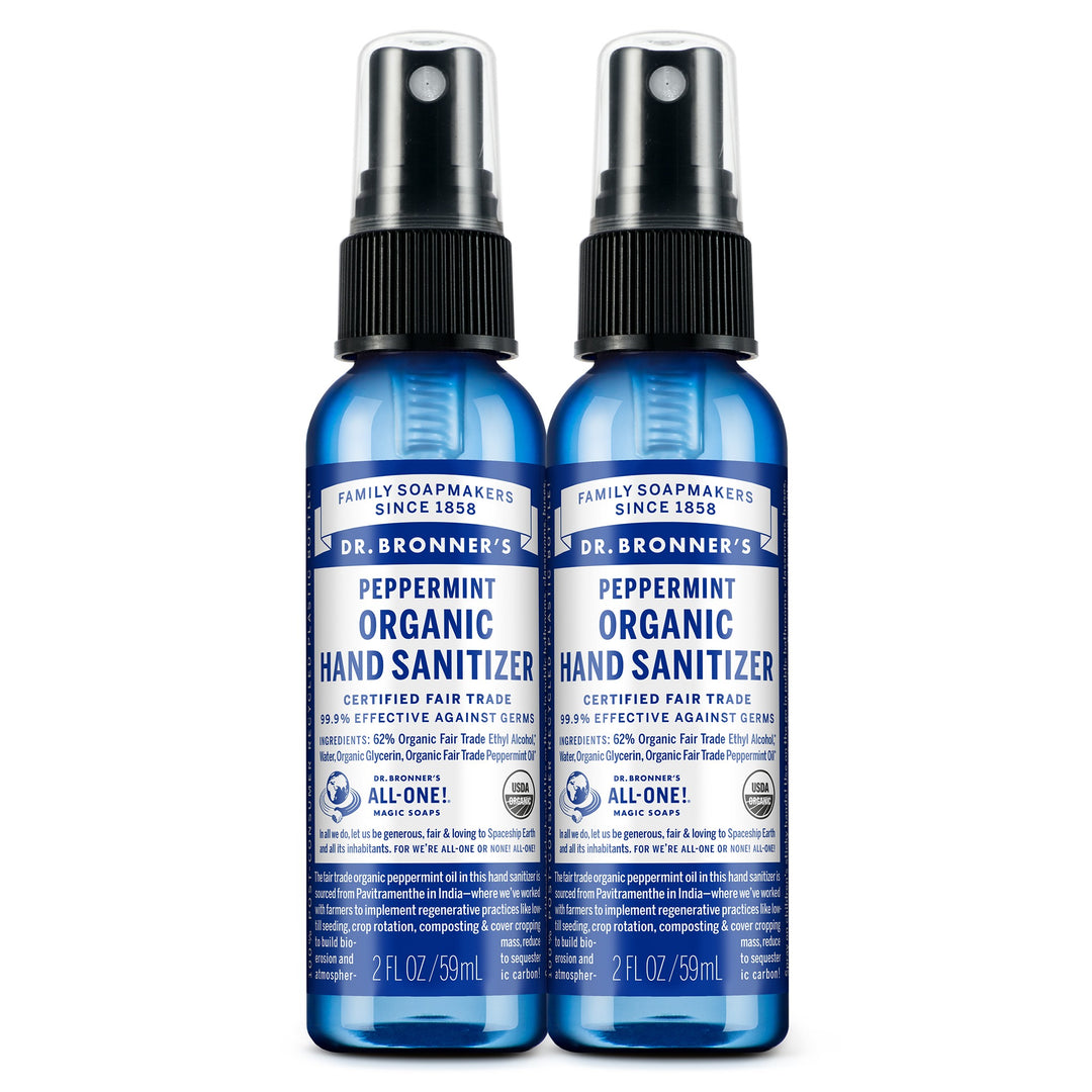 Two blue 2 fl oz bottles of Dr. Bronners Peppermint Organic Hand Sanitizer with spray tops, labeled as certified fair trade. Text reads FAMILY SOAPMAKERS SINCE 1858, PEPPERMINT ORGANIC HAND SANITIZER, CERTIFIED FAIR TRADE, and ALL ONE Ideal for eco friendly hygiene
