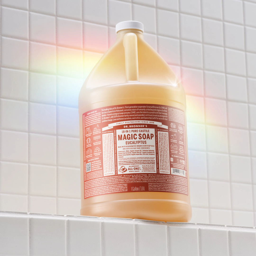 A gallon bottle of Dr. Bronners 18 in 1 Pure Castile Eucalyptus Soap stands on a tiled bathroom shelf, illuminated by a subtle rainbow light. Dr. Bronners Magic Soap Eucalyptus [1 Gallon]