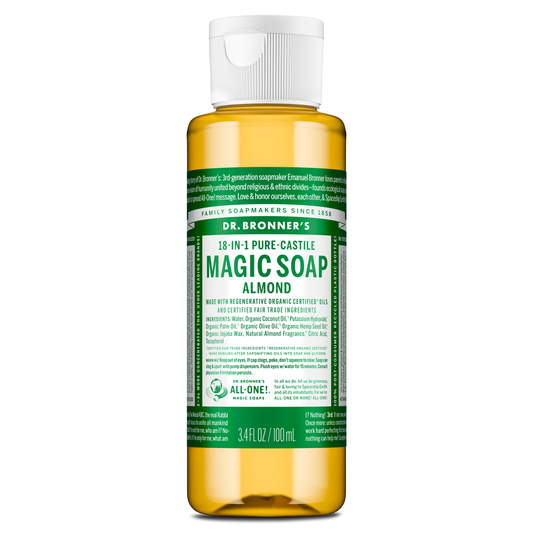 A small bottle labeled Dr. Bronners 18 in 1 Pure Castile Magic Soap Almond contains liquid castile soap in a clear container with a white flip top cap, featuring green, detailed text [3.4 oz]